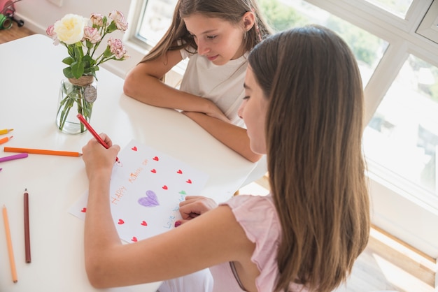 Free photo girl drawing red hearts on paper