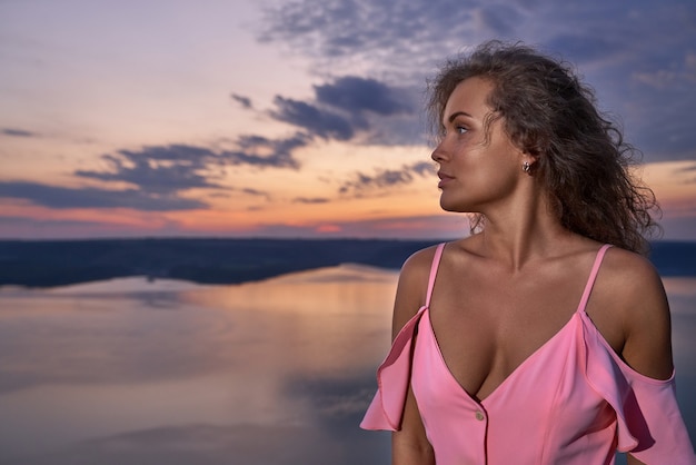 Girl in dress with bare shoulders and decollete near lake