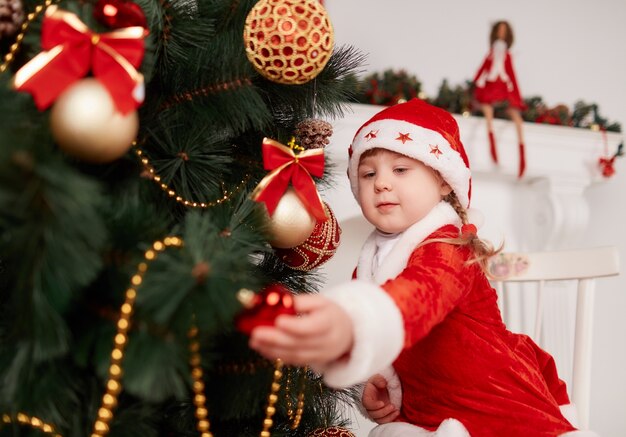 Girl dressed as santa decorating the christmas tree