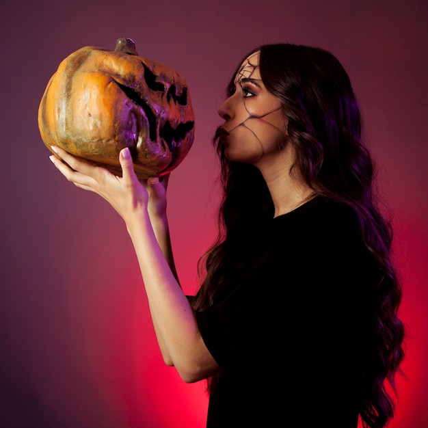 Girl dressed as witch looking at pumpkin