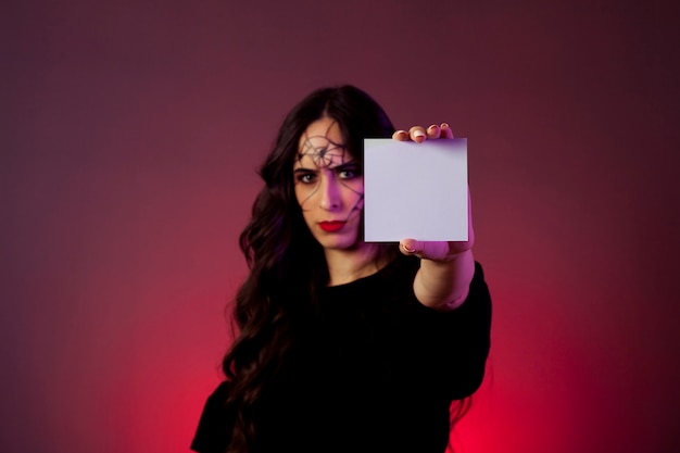 Girl dressed as witch showing card