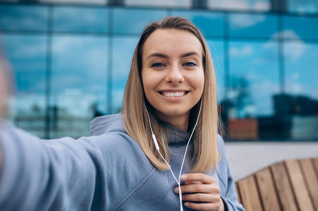 Girl in earphones taking selfie outdoors