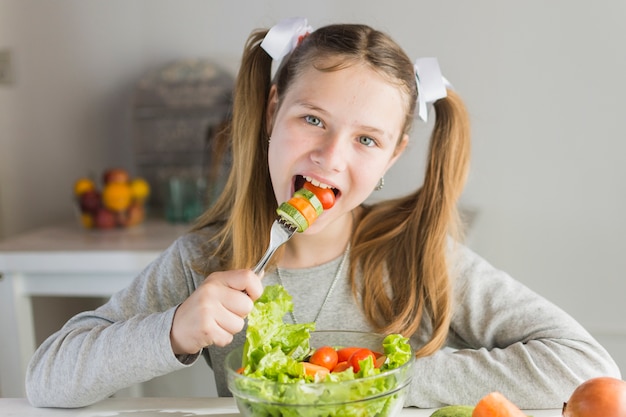 Girl eating vegetable salad with fork