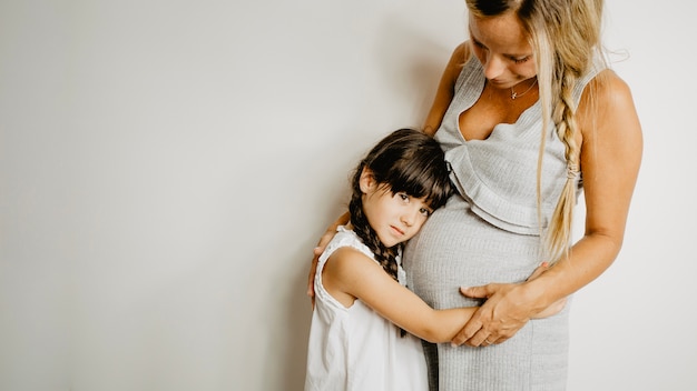 Free Photo girl embracing pregnant mother