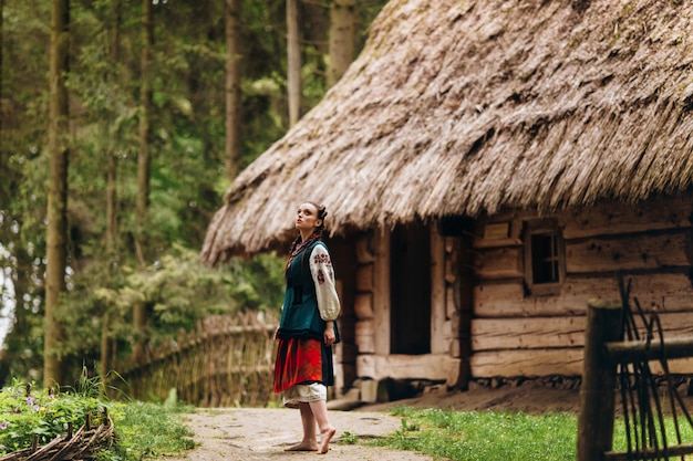 Free Photo girl in an embroidered dress is standing in the yard and looking into the sky