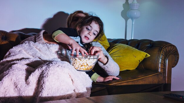 Girl enjoying evening with mother having popcorn