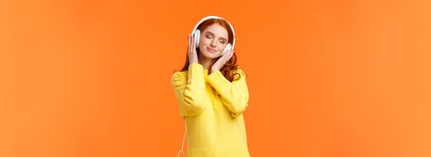 Free Photo girl enjoying nice soft sound of headphones cheerful romantic and delighted pretty redhead woman tilt head with closed eyes and tender smile carried away with music in earphones