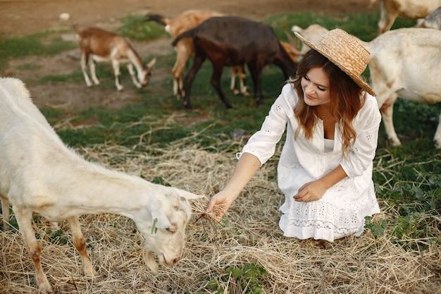 Free photo girl farmer with white goat. woman and small goat green grass. eco farm. farm and farming concept. village animals. girl play cute goat. f