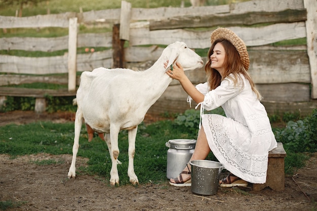 Free Photo girl farmer with white goat. woman and small goat green grass. eco farm. farm and farming concept. village animals.