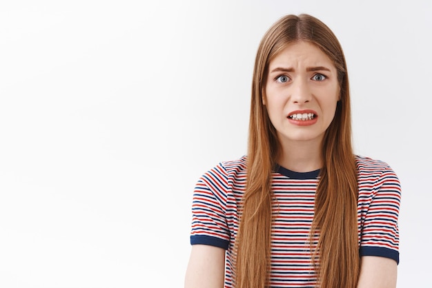 Free photo girl feeling scared of consequences look embarrassed and nervous cringe face and clench teeth frowning bothered standing concerned and anxious white background hear terrible news