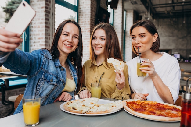 Girl friends having pizza at a bar at a lunch time