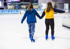 Free photo girl friends ice skating on the ice rink together