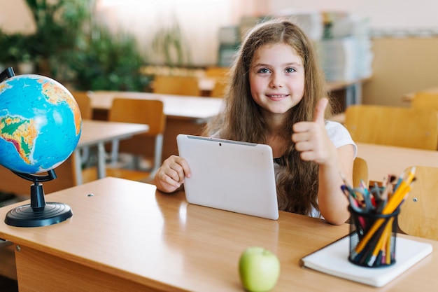 Girl gesturing thumb up with tablet