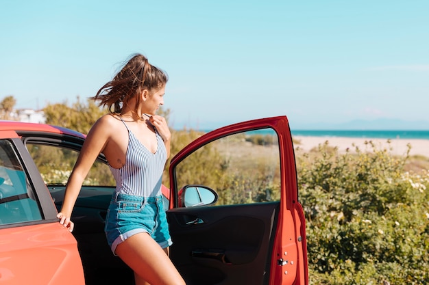 Girl getting out of car at seaside 