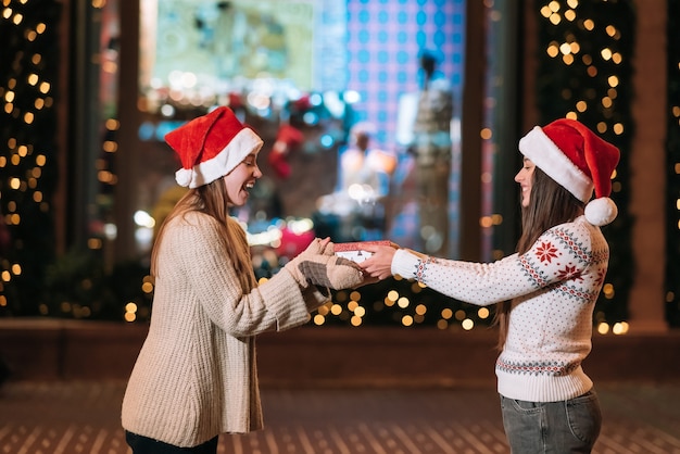 The girl gives a gift to her female friend on the street