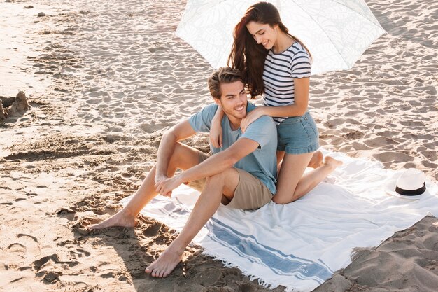 Girl giving massage to boyfriend at the beach