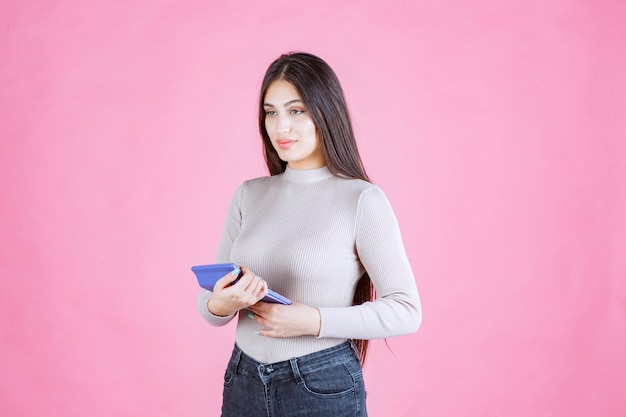 Girl in grey shirt holding a blue calculator, watching and working with it