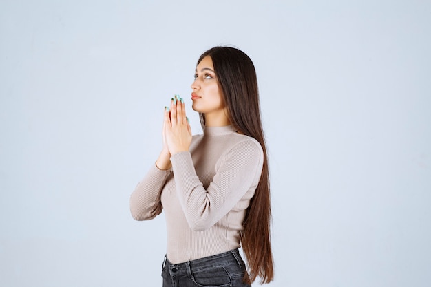 Free photo girl in grey shirt uniting her hands and praying.