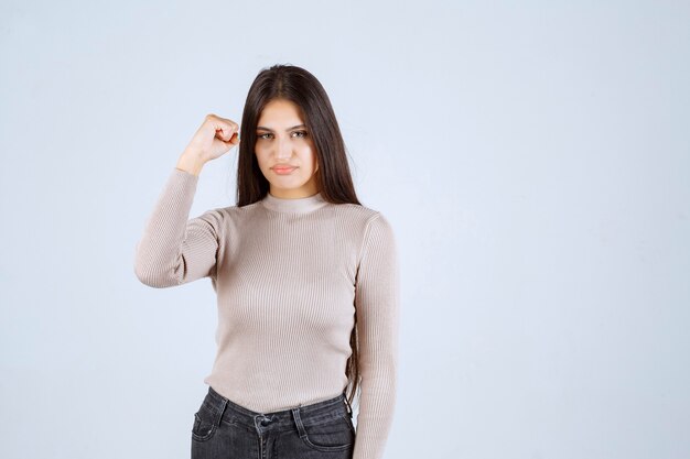 Girl in grey sweater showing her fists and power. 