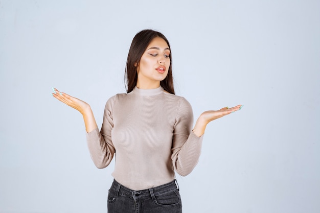 Girl in grey sweater showing something in her hand. 