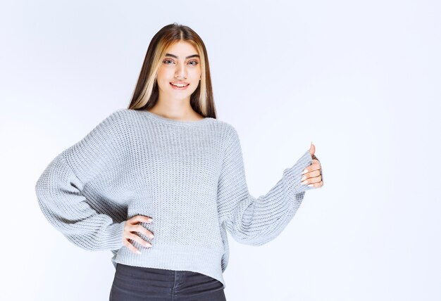 Girl in grey sweatshirt showing thumb up.