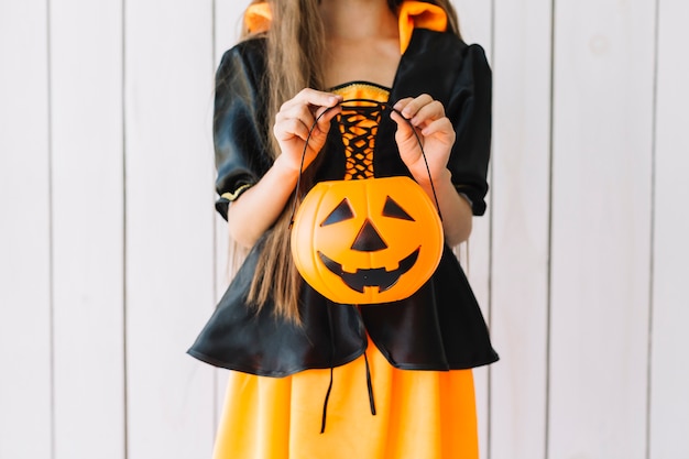 Free Photo girl in halloween costume holding pumpkin basket