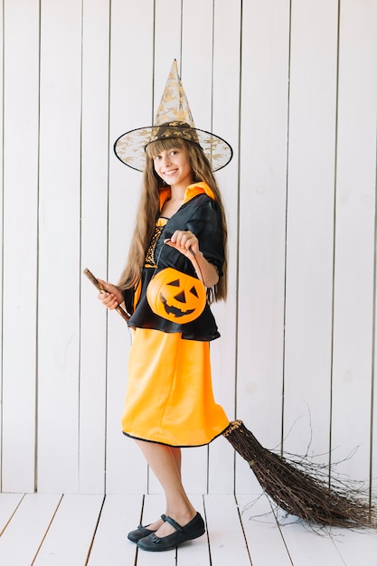 Free photo girl in halloween costume imitating broom flight in studio