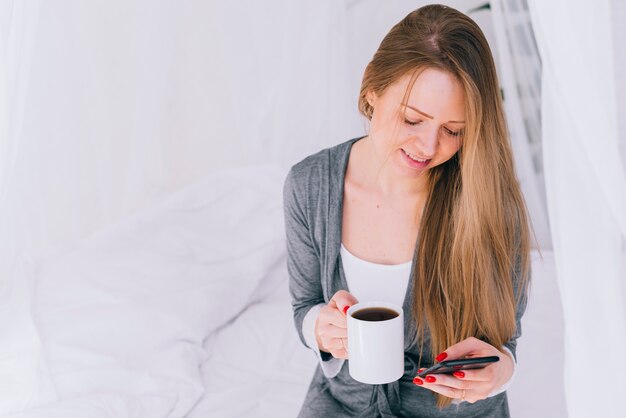 Girl having coffee with the mobile phone