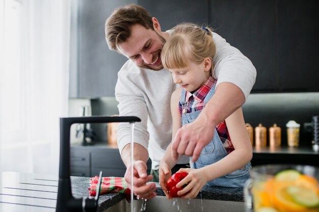 Girl helping father to wash vegetables