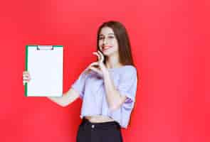 Free photo girl holding a blank reporting sheet and showing enjoyment sign.