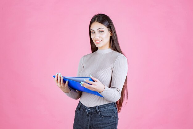 Girl holding a blue project folder and looks successful and happy