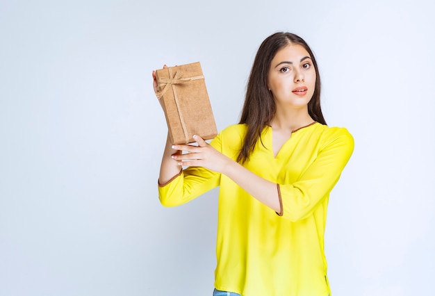 Girl holding a cardboard gift box and feeling positive.