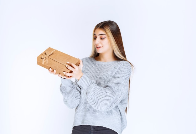 Girl holding a cardboard gift box and looks surprized.