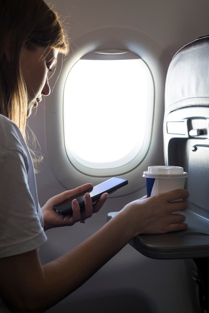 Girl holding a coffee and looking at phone