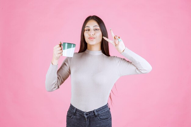 Girl holding a coffee mug and sending peace message