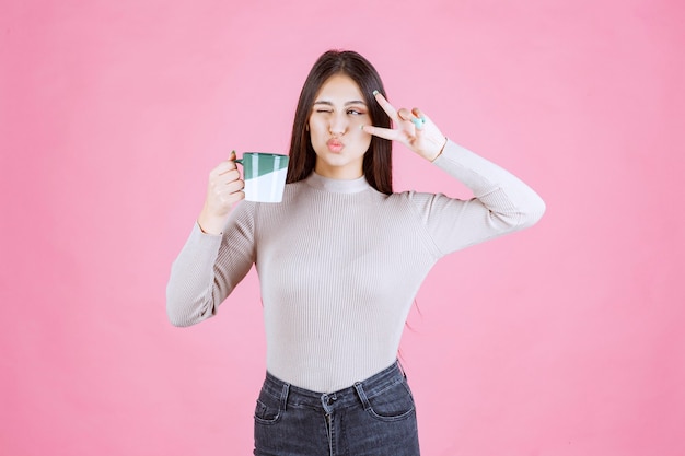 Girl holding a coffee mug and sending peace message