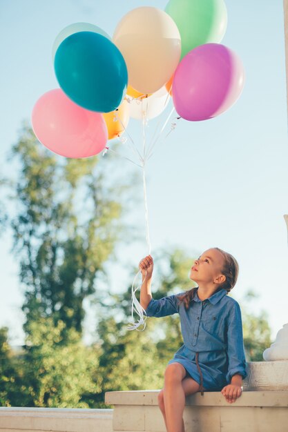 Girl holding colorful balloons looking to them