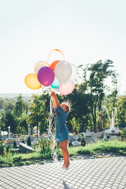 Girl holding colorful balloons stretching to the sky