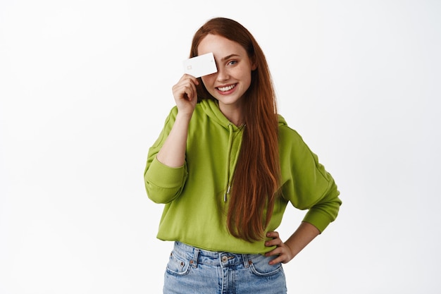 Girl holding credit card and smiling happy, concept of shopping and discounts on white