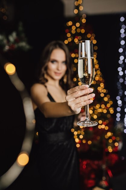 Girl holding a glass with champagne stands in a foreground