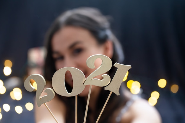 Free Photo girl holding in hand the number of the coming year on a dark blurred background.