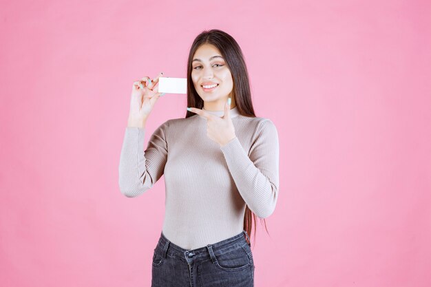 Girl holding her business card and pointing at it with finger