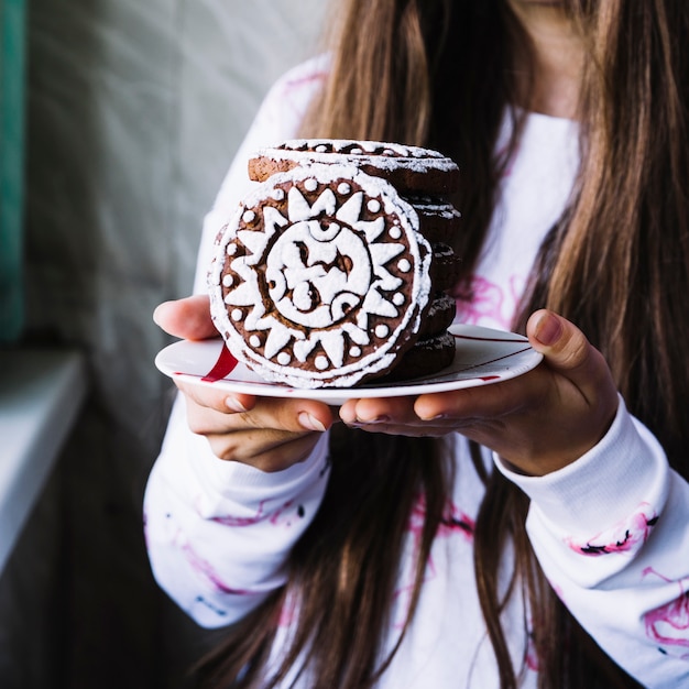 Girl holding icing cookies on plate