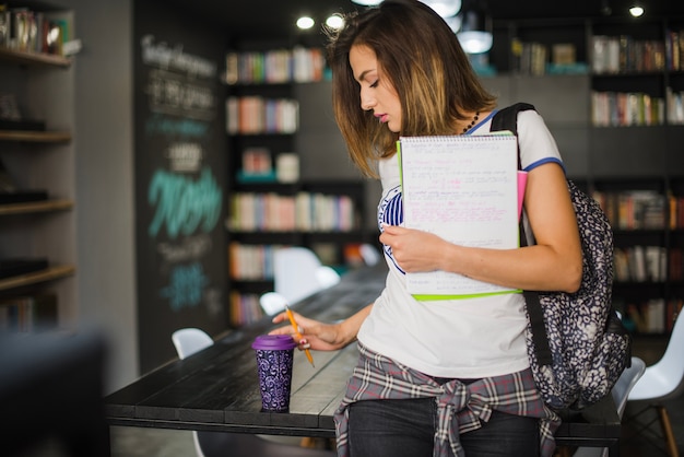 Free photo girl holding notebooks grabbing cup