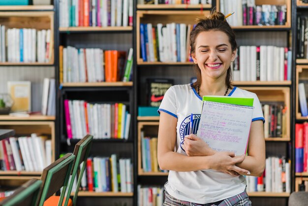 Girl holding notebooks and pen smiling