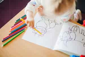 Free photo girl holding pencil sitting at table