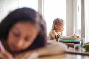 Free photo girl holding pens sitting at school desks