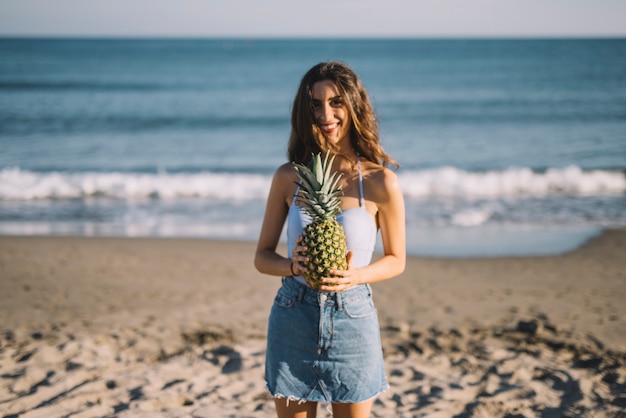 Girl holding pineapple at the beach