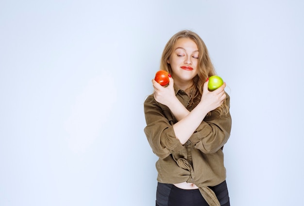 Free Photo girl holding red and green apples in both hands.