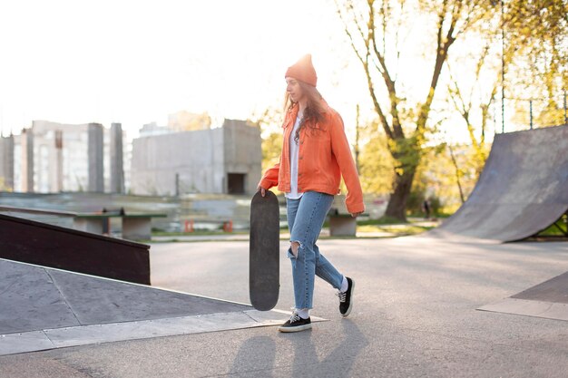 Girl holding skateboard outdoors full shot